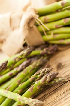 Fresh healthy green asparagus as a close-up on a wooden table in sunlight
