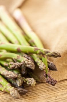 Fresh healthy green asparagus as a close-up on a wooden table in sunlight
