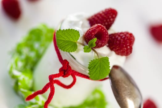 Fresh yoghurt with raspberries in a glass insulated on a white background