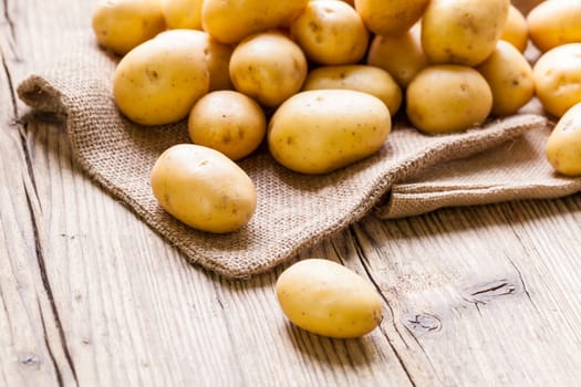 Fresh new potatoes on a jute sack with a green background as a close-up