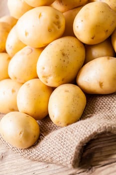 Fresh new potatoes on a jute sack with a green background as a close-up