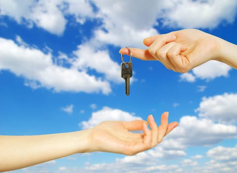 Hands with key on a background sky