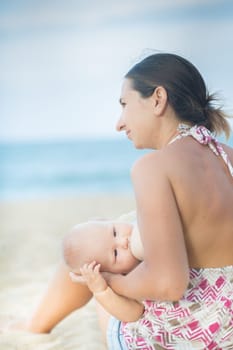 Mother breastfeeding baby on the beach