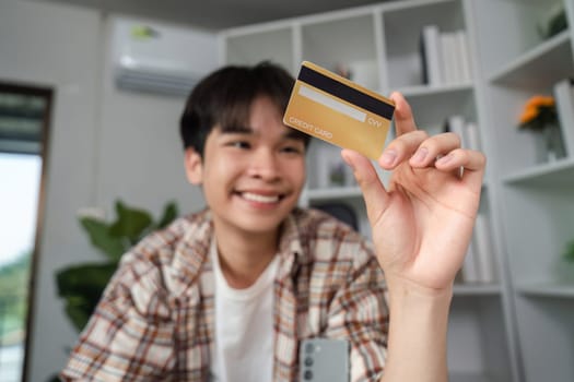 A cheerful young man displays his credit card, representing financial empowerment and the convenience of online shopping.
