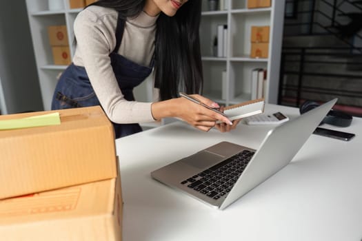 An entrepreneur organizes packages and takes notes in a contemporary office space reflecting effective business practices.