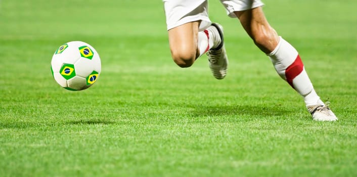 Soccer player runing after the ball with Brazil flag