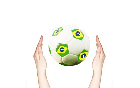 Hands holding soccer ball with the colors of Brazil flag