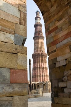 Qutub Minar and Iron Pillar viewed though stone wall corner and arch, Delhi, India, Asia