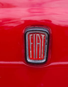 close-up of an old fiat logo on a red car. In honor of the 100th anniversary in 1999, the logo was modernized.