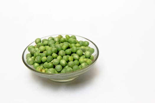 Glass dish containing fresh green peas, isolated on white