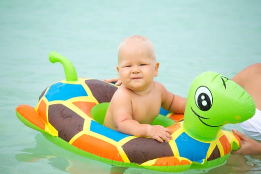 Baby bathing in the sea with swim ring