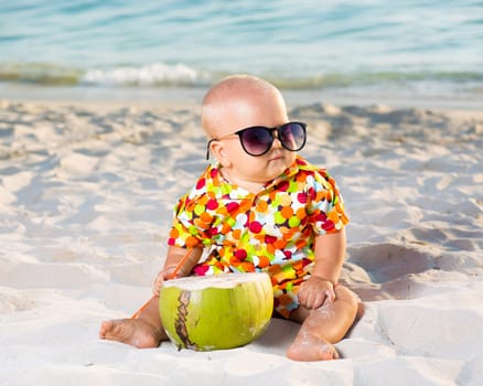 Funny baby wearing sunglasses with coconut