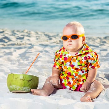 Funny baby wearing sunglasses with coconut