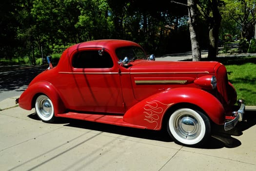 An old classic red car from the 1940 sitting on a driveway..