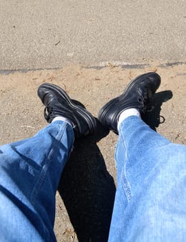 The legs of a tired hiker sitting on a bench, resting from his walk..
