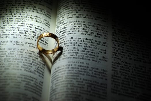 Wedding ring and heart shaped shadow over a Bible