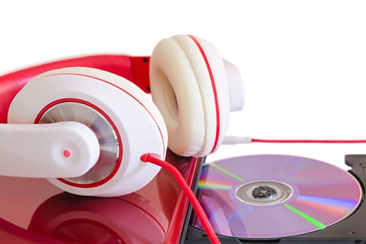 Language course learning with DVD compact disc in laptop and white red headphones on glossy notebook surface
