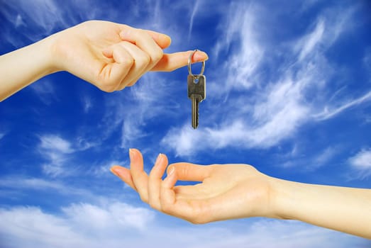 Hands with key on a background sky