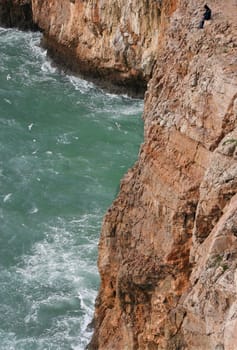 Severe dramatic seascape with fisherman in Cape Saint Vicent cliffs, Portugal