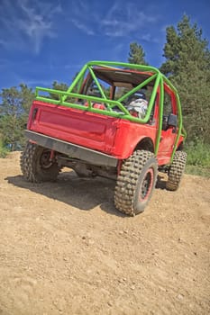Red offroad car on the dusty terrain.Processed as a photo with highlighted details.All potential trademarks are removed.