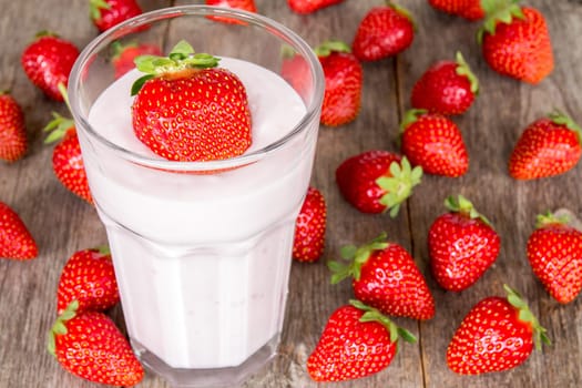 Strawberry pink cocktail in a glass and strawberries on wood background