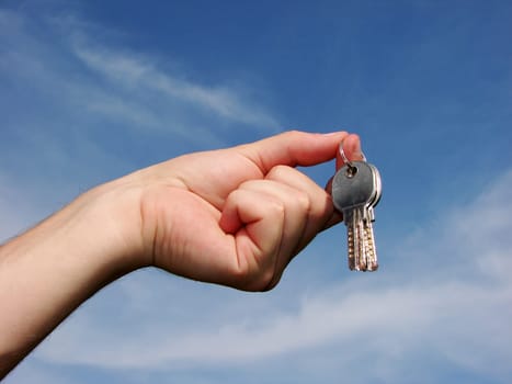 Hands with key on a background sky