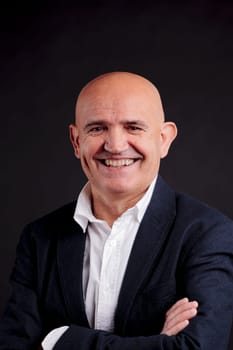 old bald self-confident businessman on a dark background