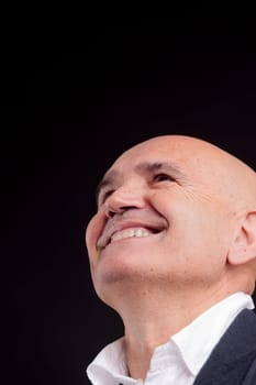 old bald self-confident businessman on a dark background