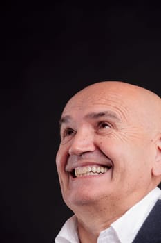 old bald self-confident businessman on a dark background