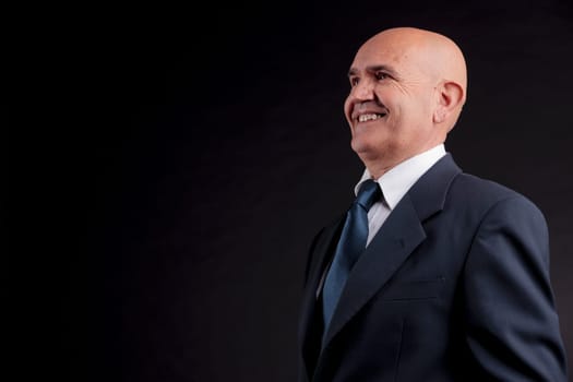 old bald self-confident businessman on a dark background