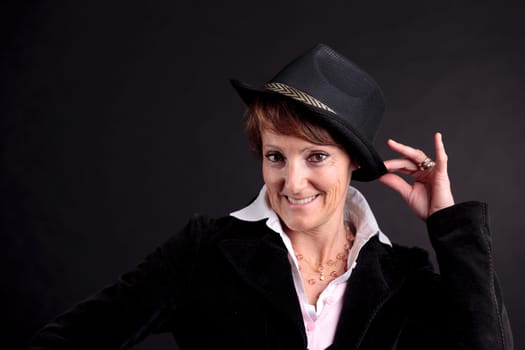 an old white woman smiling while holding up a black fashion hat