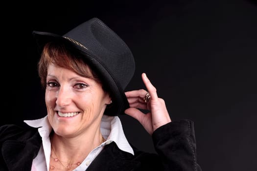 an old white woman smiling while holding up a black fashion hat