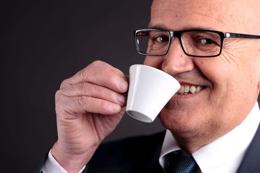 bald old smiling businessman holding a cup of espresso italian coffee