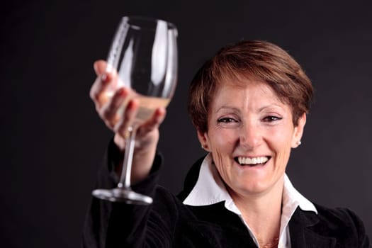 pretty old woman rising up a glass of wine with glaze on camera with focus on face