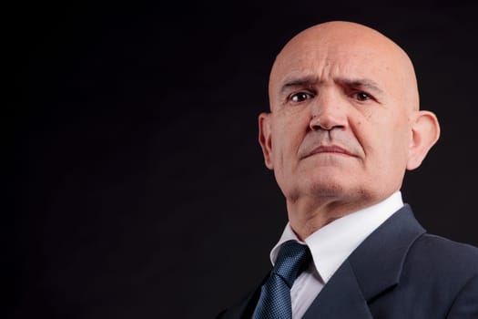 old bald self-confident businessman on a dark background