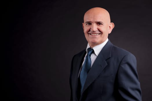 old bald self-confident businessman on a dark background