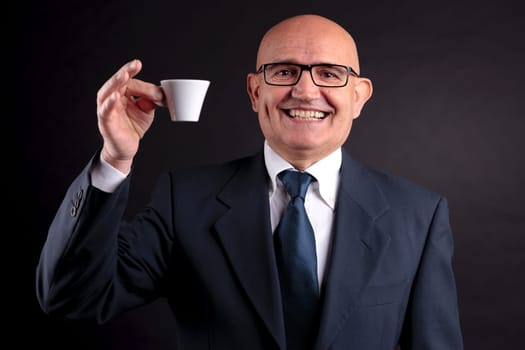 bald old smiling businessman holding a cup of espresso italian coffee