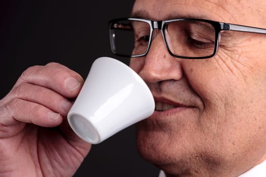 bald old smiling businessman holding a cup of espresso italian coffee