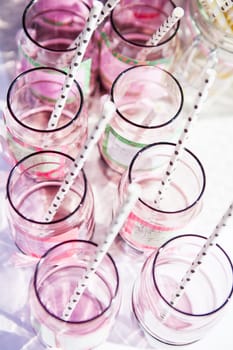 Closeup of decorative pink colored party glasses with straws on table outdoors on bright day