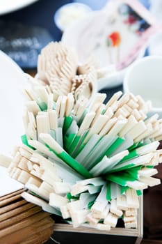 Closeup of bunch of wooden chopsticks on table outdoors ready for use at party with forks in background