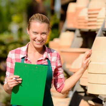 Garden center woman worker standing by clay pots shelf smiling