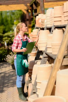 Garden center woman worker make inventory of clay pots sunny
