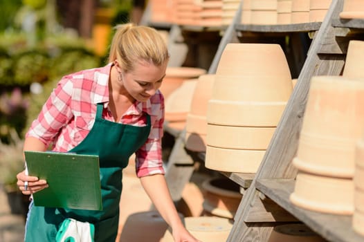 Garden center woman looking down at clay pots sunny day