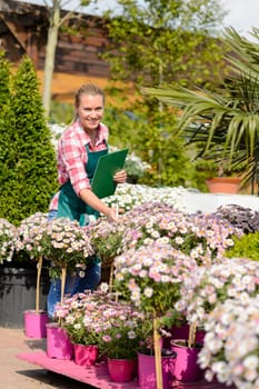Happy woman make inventory potted flowers at garden shopping center