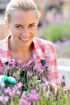 Smiling woman with purple flower working in garden center
