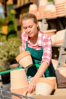 Garden center woman worker putting clay pots on shopping cart