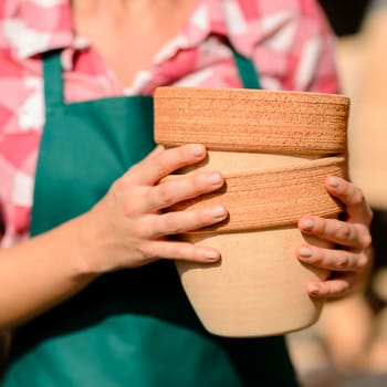 Close-up of garden center worker hands holding two clay pots