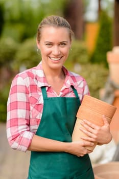 Smiling garden center woman worker holding clay pots portrait
