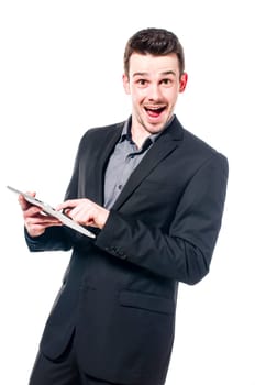 Young businessman in suit typing on a tablet computer and laughing at the camera, isolated on white.