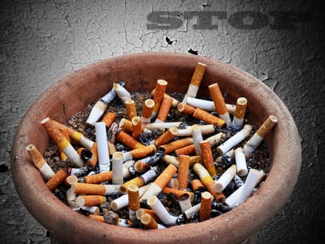 Cigarette addiction in ashtray on old wall  background